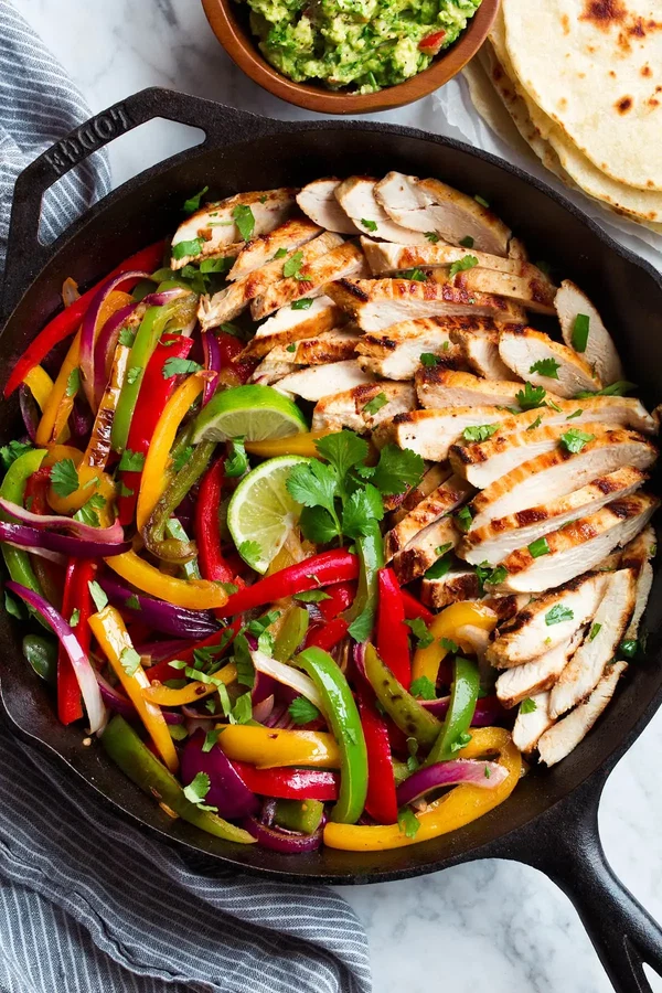 Cast-iron skillet of chicken fajitas with grilled chicken, peppers and onions, plus guacamole and tortillas from Meal Prep Ottawa